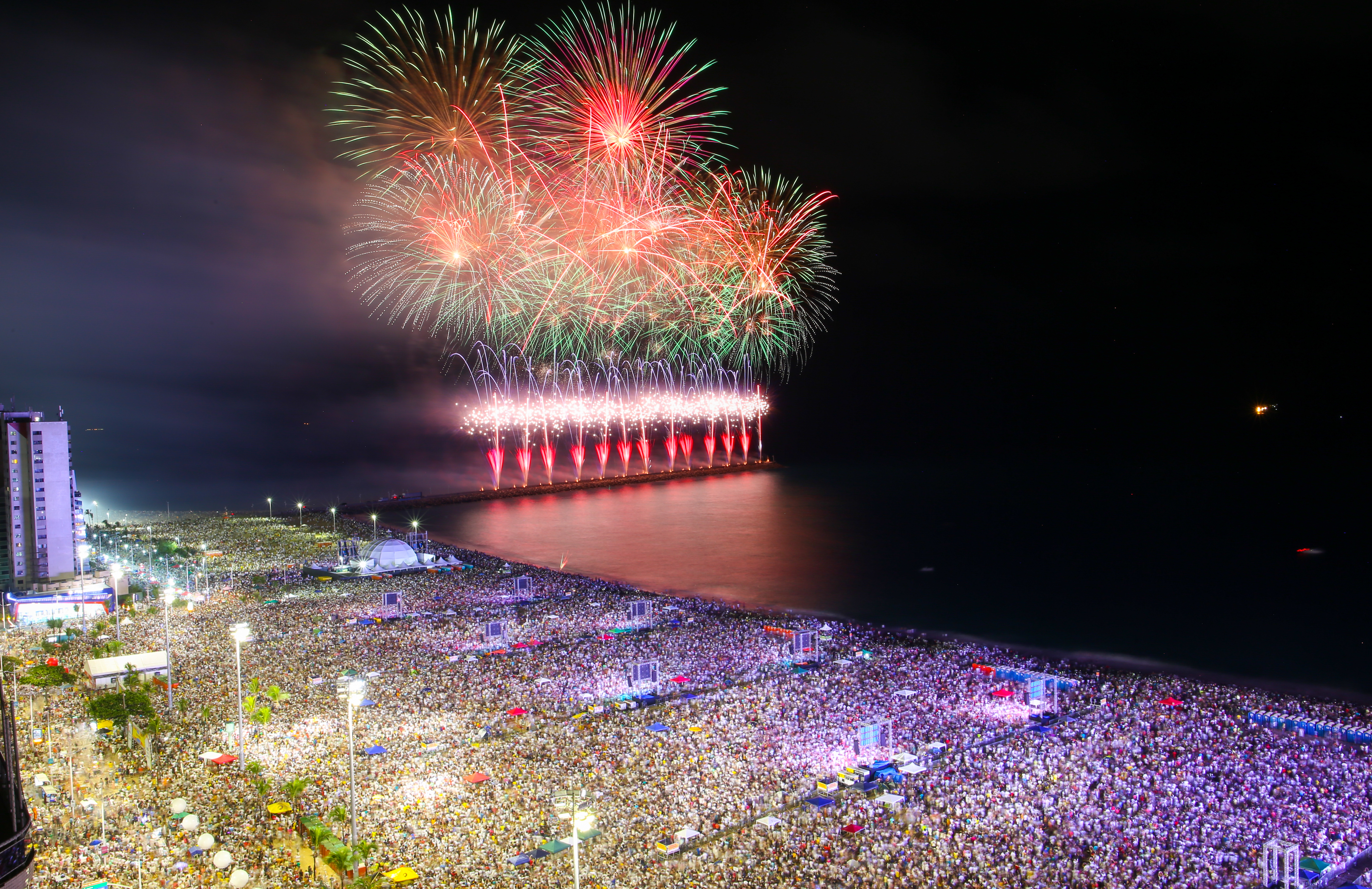 multidão de pessoas e fogos ao fundo no mar